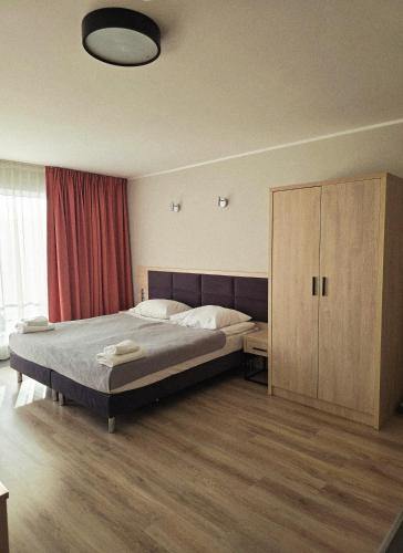a bedroom with a large bed and a cabinet at Dominikana Apartament 41b in Sianozety
