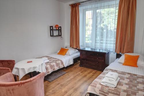 ein Zimmer mit zwei Betten, einem Tisch und einem Fenster in der Unterkunft Hotel Monttis in Sucha Beskidzka