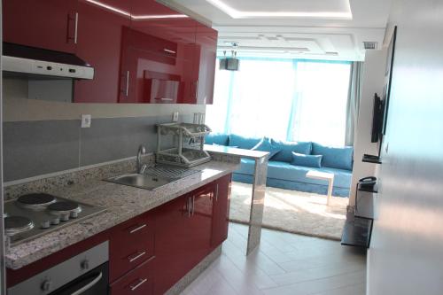 a kitchen with red cabinets and a blue couch at Résidence La Place in Laayoune