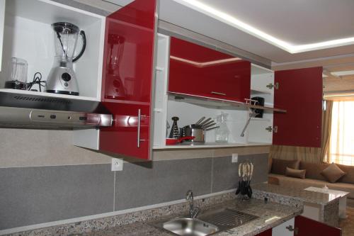 a kitchen with red cabinets and a sink at Résidence La Place in Laayoune