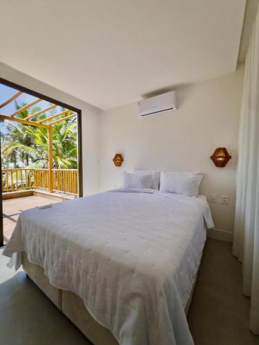 a bedroom with a large white bed and a balcony at Casa Baião in Fortim