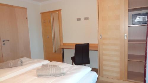 a room with two beds and a chair and a desk at Appartements Gassner in Bruck an der Großglocknerstraße