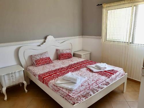 a white bed with red and white sheets and pillows at Ponta Preta Village 10 in Vila do Porto