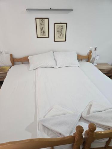a bed with white sheets and two pictures on the wall at APARTMANSKI SMEŠTAJ SOLARIS kod Aqua Parka STUDIO APARTMANI in Soko Banja