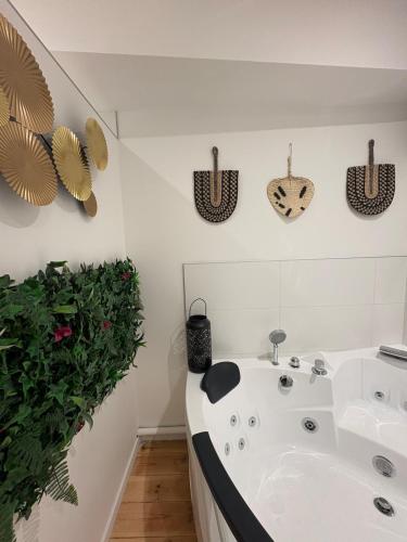 ein Badezimmer mit einer weißen Badewanne und einer grünen Pflanze in der Unterkunft Le Cocon Central avec Balnéo in Roanne