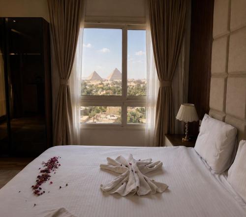 a white bed with a flower on it in front of a window at Pyramids Sunshine View in Giza