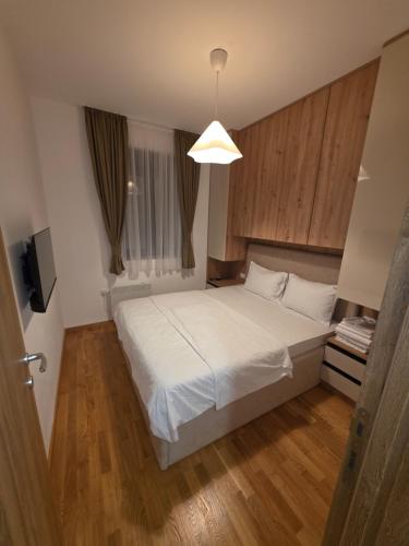 a bedroom with a white bed and a light at Vila#Borova#800m in Zlatibor