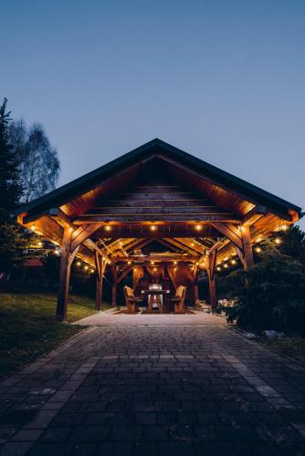 a wooden pavilion with a picnic table and lights at Zacisze Krzeszów in Krzeszów