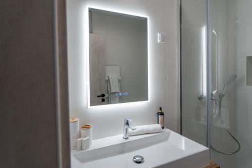 a white bathroom with a sink and a shower at AApartman Prime in Pécs