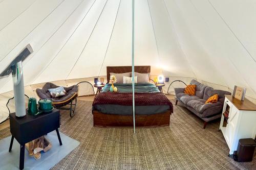 a bedroom in a tent with a bed and a couch at Creekside Retreat at Triangle Lake in Blachly