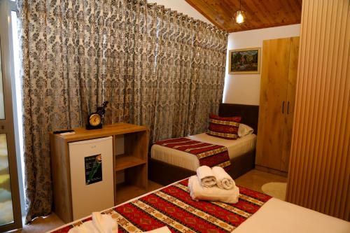 a small room with two beds and a desk and a room with two towels at Lake Bliss Cabins in Shkodër