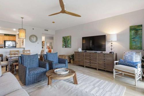 a living room with blue chairs and a flat screen tv at Easy Beach Walk Pools and Hot Tubs in Destin