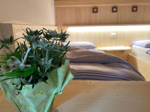 a vase with flowers on a table next to a bed at Garni al Barance in Selva di Cadore
