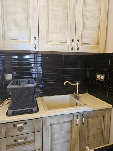 a kitchen with a sink and a black tile wall at Amfitrion on the Town in Gythio