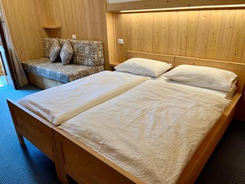 a bedroom with a large bed and a chair at Garni al Barance in Selva di Cadore