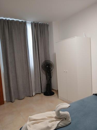 a bedroom with a bed and a window with a fan at ATICO ACOGEDOR LA LAGUNa in Las Lagunas