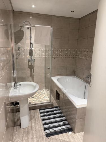 a bathroom with a tub and a sink and a shower at Be my guest in Roodepoort