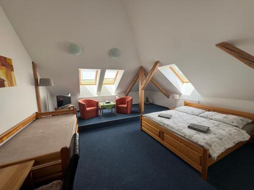 a bedroom with a bed and two red chairs at Penzion U Peňázů in Tři Studně