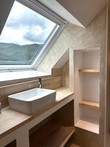 a bathroom with a white sink and a window at Bel appartement sous combles in Argelès-Gazost
