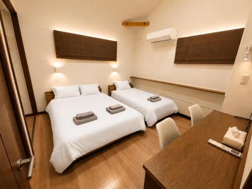 a small room with two beds and a table at House Villa Koharu in Asahikawa