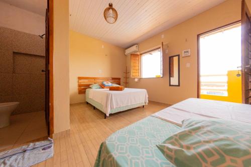 a bedroom with two beds and a bathroom at Pousada Costa do Mar in Luis Correia