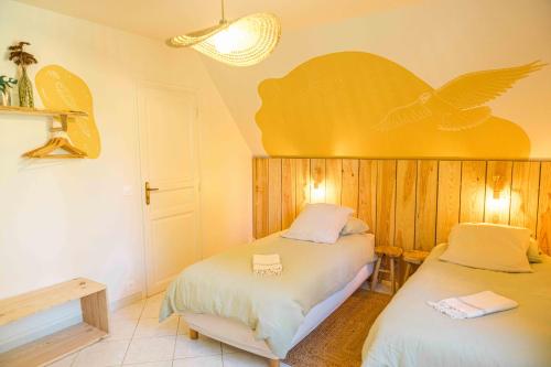 a bedroom with two beds with a bird on the wall at Maison Forenea chambres d'hôtes dans les bois avec petits déjeuners BIO in Sainte-Nathalène