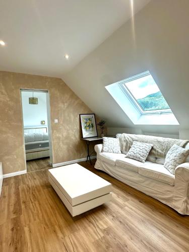 a living room with a white couch and a skylight at Bel appartement sous combles in Argelès-Gazost