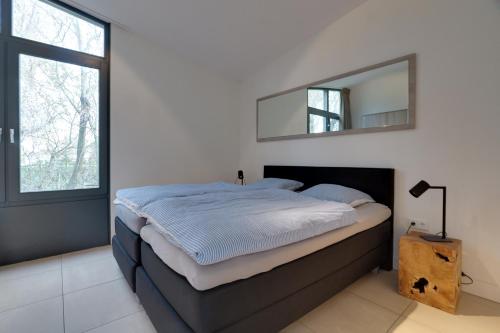 a bedroom with a bed with a mirror on the wall at Knookborst in Hollum