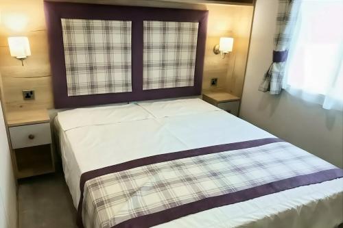 a bedroom with a large bed with a window at Spacious Caravan - Durdle Door Holiday Park in West Lulworth