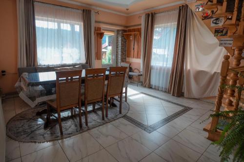 a dining room with a table and chairs and windows at Лісова казка in Yaremche