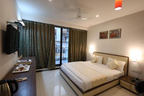 a bedroom with a bed and a large window at MB hotel in Rajkot