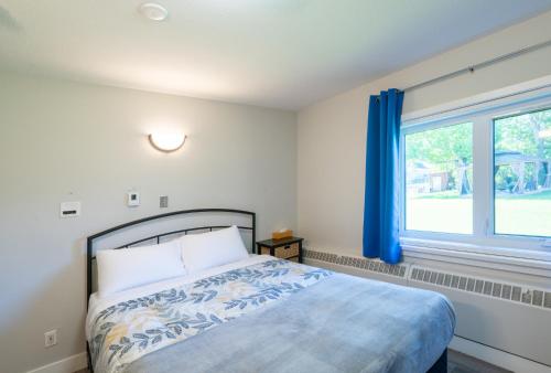 a bedroom with a bed and a window with blue curtains at Nekinan Lodge in Smoky Lake