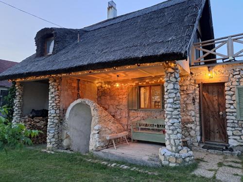 a stone house with a thatched roof and a porch at Baglyashegy Vendégház in Sümeg