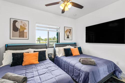 a bedroom with two beds and a flat screen tv at Sunset Villa w Pool, Outdoor kitchen & Grill in Hialeah