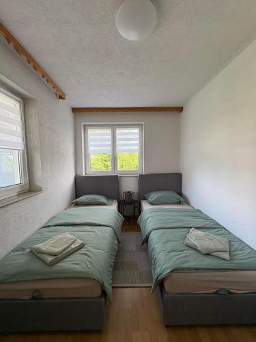 two beds in a room with two windows at Vila Ziki in Sarajevo