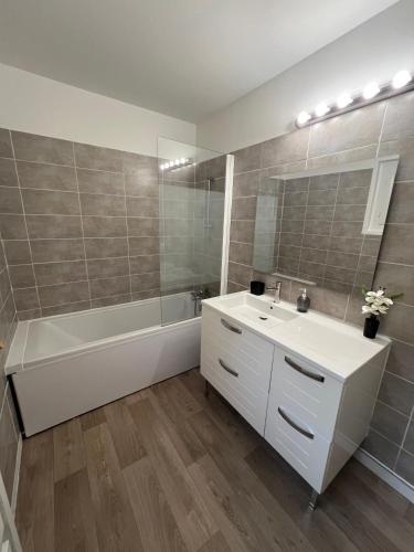 a bathroom with a tub and a sink and a bath tubermott at La Maison de Miel in Beynat