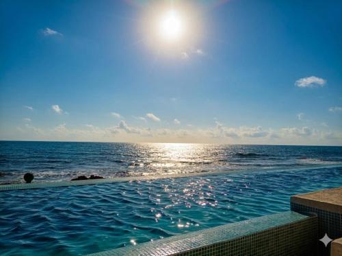 Ein Swimmingpool mit dem Meer im Hintergrund in der Unterkunft The Mint Resort Isla Mujeres in Isla Mujeres
