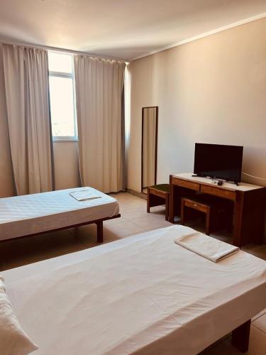 a room with two beds and a desk with a computer at Hotel Mata da Praia in Vitória