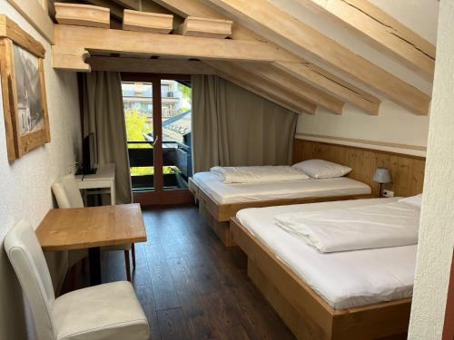 a room with two beds and a table and a chair at Kronenlodge in Seefeld in Tirol