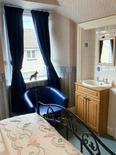 a bathroom with a blue chair and a sink at Kinkell House in Inverness