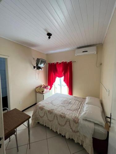 a bedroom with a bed and a window with a red curtain at Hotel e restaurante Camicia in Maximiliano de Almeida