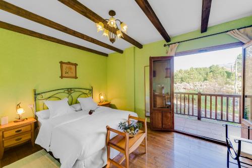 1 dormitorio con cama blanca y balcón en Los Montejos & Spa, en Valverde del Fresno