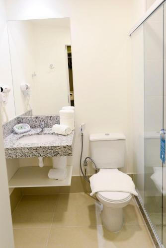 a bathroom with a toilet and a sink and a mirror at Tulip Inn Vila Velha in Vila Velha