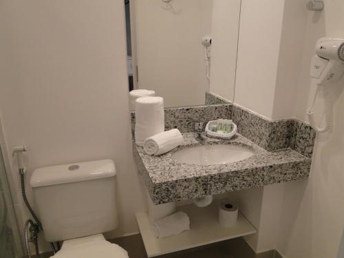 a bathroom with a sink and a toilet and a mirror at Tulip Inn Vila Velha in Vila Velha