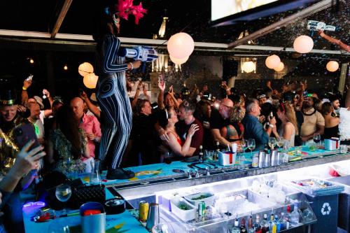 a crowd of people standing around a bar at a party at Tantalo Hotel - Kitchen - Roofbar in Panama City