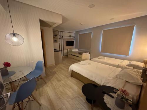 a bedroom with a large bed and a table and chairs at Hotel Flat Guarulhos 5 in Guarulhos