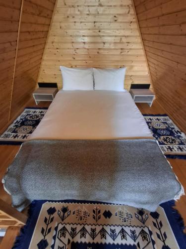 a bed in a room with two rugs at Cabanele Avoca in Avrig