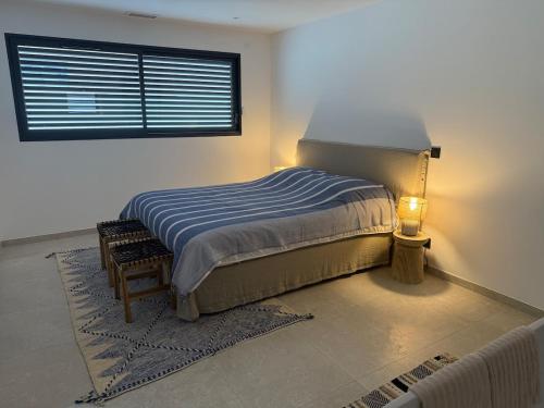 a bedroom with a bed with a lamp and a window at L'Annexe de la Subérine in Vivès