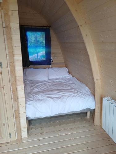 a bed in a wooden room with a window at Houx POD in Saint-Racho