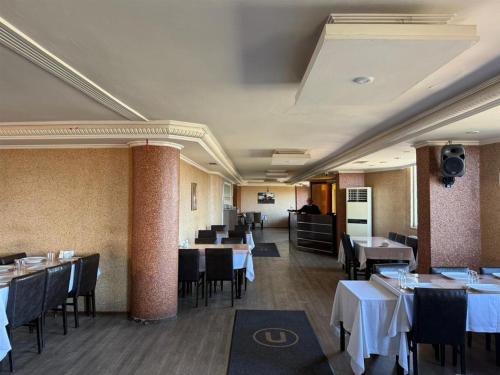 a dining room with tables and chairs with white tablecloths at Otel Ustabaş in Hopa